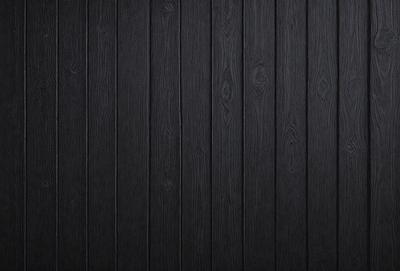The primary subject of the image is a wooden wall. The setting is a dark room, and the visual style is a photo. The dominant colors are black and brown, creating a moody atmosphere.