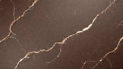 The primary subject of the image is a marble countertop with a gold-like pattern. The setting is a kitchen, and the visual style is a photo. The countertop has a brown and gold color scheme, giving it a warm and luxurious appearance.