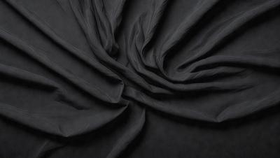The primary subject of the image is a black fabric, which appears to be a piece of cloth or a curtain. The setting is a dark background, which contrasts with the fabric. The visual style is a close-up of the fabric, showcasing its texture and details. The colors and mood of the image are predominantly dark, with the black fabric being the main focus.