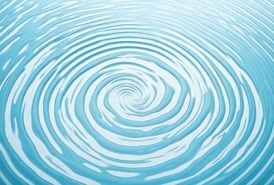 The primary subject of the image is a swirling, spiraling, or circular pattern of water. The setting is a large body of water, possibly an ocean or a lake. The visual style is a close-up of the water, showcasing the intricate pattern and movement. The colors and mood of the image are predominantly blue, creating a serene and calming atmosphere.