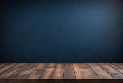 The primary subject of the image is a wooden table with a blue wall in the background. The table appears to be a wooden plank, and the blue wall adds a contrasting color to the scene. The visual style of the image is a photo, capturing the wooden table and the blue wall in a realistic manner. The colors and mood of the image are predominantly blue, creating a calm and serene atmosphere.