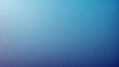 The primary subject of the image is a large, empty, and dark blue sky. The setting is a vast, open space with no visible landmarks or objects. The visual style is a realistic representation of the sky, with no indication of digital art or illustration. The colors and mood of the image are predominantly dark and moody, with the blue sky creating a sense of vastness and emptiness.