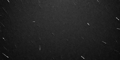 The primary subject of the image is a black leather surface. The setting is a dark room, and the visual style is a close-up of the leather surface. The colors and mood of the image are predominantly dark and moody, with the black leather providing a striking contrast against the dark background.