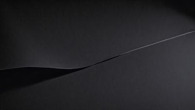 The primary subject of the image is a black background with a white line or a white object on it. The setting appears to be a dark room, and the visual style is a close-up of the white line or object. The colors and mood of the image are predominantly dark and moody, with the white line or object standing out against the black background.
