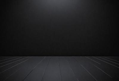The primary subject of the image is a black background with a light source shining on it. The setting is a dark room, and the visual style is a black and white photo. The colors and mood of the image are predominantly dark and moody, with the light source creating a contrasting effect.