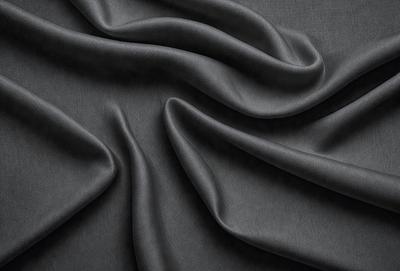 The primary subject of the image is a piece of fabric, which appears to be a gray or black material. The setting is a close-up view of the fabric, showcasing its texture and pattern. The visual style is a detailed, up-close representation of the fabric. The colors and mood of the image are predominantly dark, with the gray or black fabric creating a moody atmosphere.