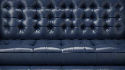 The primary subject of the image is a blue leather couch. The setting is a dark room, and the visual style is a photo. The dominant colors are blue and black, creating a moody atmosphere.