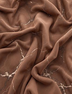 The primary subject of the image is a close-up of a brown fabric, possibly a piece of leather or a marbled material. The setting is a marbled surface, which adds to the visual style of the image. The colors and mood of the image are predominantly brown, giving it a warm and earthy feel.