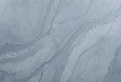 The primary subject of the image is a marble countertop with a patterned design. The setting is a kitchen or bathroom, as the countertop is a part of the counter. The visual style is a photo, showcasing the natural texture and patterns of the marble. The colors and mood of the image are predominantly grays and whites, giving it a clean and elegant appearance.