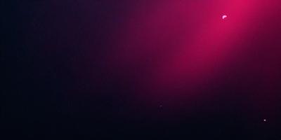 The primary subject of the image is a red background, which creates a striking contrast with the darker surroundings. The setting appears to be a dark room, with the red background serving as a focal point. The visual style of the image is a combination of photo and digital art, as it captures the vibrant red hue and the contrasting darkness. The colors and mood of the image are predominantly dark and moody, with the red background providing a burst of color and energy.