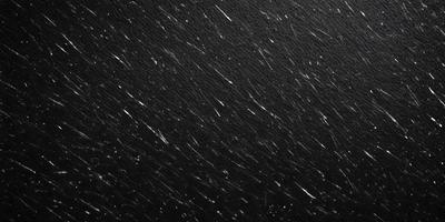 The primary subject of the image is a black background with a few white streaks. The setting is a night sky, and the visual style is a black and white photo. The colors and mood of the image are predominantly dark and moody, with the white streaks adding a touch of brightness.
