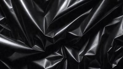 The primary subject of the image is a close-up of a black fabric, possibly a piece of clothing or a curtain. The setting is a dark background, which emphasizes the fabric's texture and pattern. The visual style is a close-up, which highlights the fabric's details. The colors and mood of the image are predominantly dark, with the black fabric being the main focus.