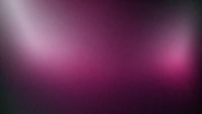 The primary subject of the image is a purple background. The setting is a dark room, and the visual style appears to be a photo. The dominant colors are purple and pink, creating a moody and atmospheric mood.