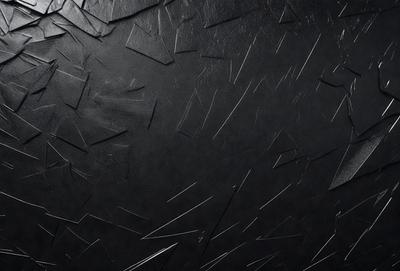 The primary subject of the image is a black leather surface with a pattern of metal spikes or nails. The setting is a dark room, and the visual style appears to be a close-up of the leather surface. The dominant colors are black and silver, creating a moody and dramatic atmosphere.