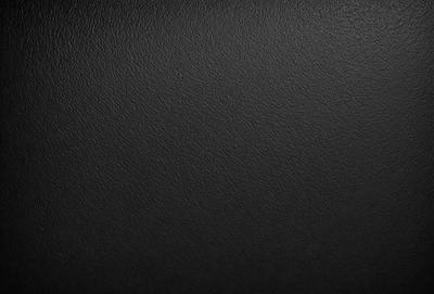 The primary subject of the image is a black leather seat. The setting is a black background, which creates a contrast with the leather seat. The visual style is a close-up of the leather seat, showcasing its texture and details. The colors and mood of the image are predominantly black, giving it a sleek and modern appearance.