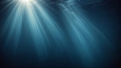 The primary subject of the image is a blue ocean with sunlight shining through the water. The setting is underwater, with the sunlight creating a beautiful and serene atmosphere. The visual style is a photo, capturing the natural beauty of the ocean and the sunlight. The colors and mood are predominantly blue, with the sunlight adding a touch of warmth and brightness to the scene.