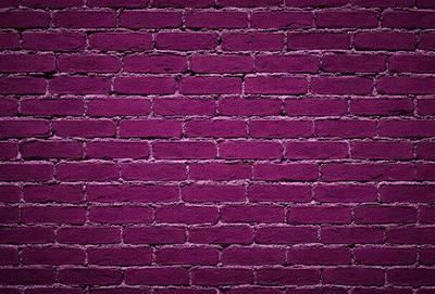 The primary subject of the image is a purple brick wall. The setting is a brick wall, and the visual style is a photo. The dominant colors are purple and pink, creating a warm and inviting atmosphere.