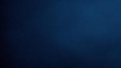 The primary subject of the image is the night sky, which is depicted in a dark blue hue. The setting is a vast, open space with no visible landmarks or objects. The visual style is a natural, realistic representation of the night sky. The colors and mood convey a sense of tranquility and serenity, as the sky is void of any distractions or light sources.