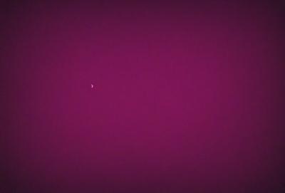 The primary subject of the image is a single moon, which is located in the upper left corner of the frame. The setting is a purple background, which creates a unique and striking visual effect. The visual style of the image is a combination of photo and digital art, as it captures the beauty of the moon against a vibrant, pink sky. The colors and mood of the image are predominantly purple, which gives it a dreamy and serene atmosphere.
