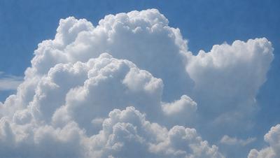 The primary subject of the image is a cloudy sky filled with large, fluffy clouds. The setting is a blue sky, which provides a contrasting background to the clouds. The visual style of the image is a photo, capturing the beauty of the cloudy sky. The colors and mood of the image are predominantly white and gray, giving it a serene and peaceful atmosphere.