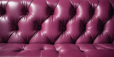 The primary subject of the image is a purple leather couch with a pinkish hue. The couch is the main object in the scene, and it is placed against a wall. The visual style of the image is a close-up of the couch, showcasing its texture and color. The colors and mood of the image are predominantly purple and pink, creating a warm and inviting atmosphere.