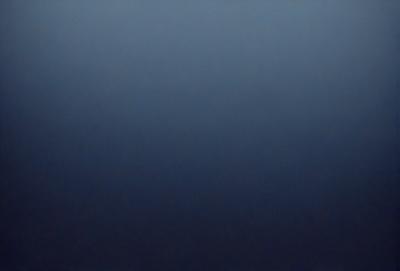The primary subject of the image is a large, dark blue sky. The setting is a vast, open space with no visible landmarks or objects. The visual style is a natural, untouched landscape. The colors and mood are predominantly dark and moody, with the blue sky serving as the main focal point.