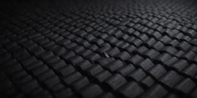 The primary subject of the image is a close-up of a black fabric with a pattern of small squares. The setting is a black background, and the visual style appears to be a photo. The dominant colors are black and white, creating a simple and elegant atmosphere.