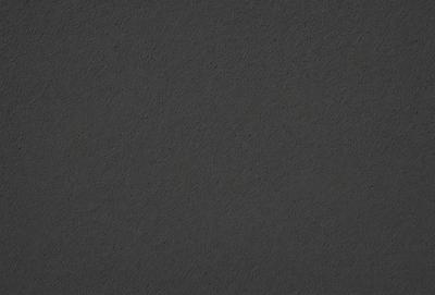 The primary subject of the image is a dark grey surface, which appears to be a leather-like material. The setting is a black background, and the visual style is a close-up of the material. The colors and mood of the image are dark and moody, with the grey surface being the dominant color.