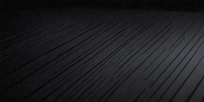 The primary subject of the image is a black surface with a pattern of thin, white lines. The setting appears to be a dark room, and the visual style is a close-up of the pattern. The dominant colors are black and white, creating a mood of simplicity and contrast.