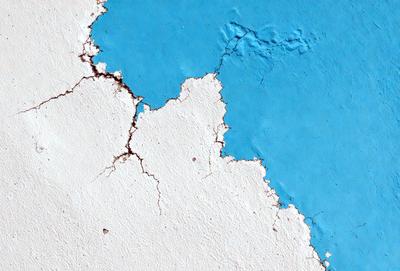The primary subject of the image is a blue wall with white chips and cracks. The setting is a room with a blue wall, and the visual style is a photo. The dominant colors are blue and white, creating a calm and soothing atmosphere.