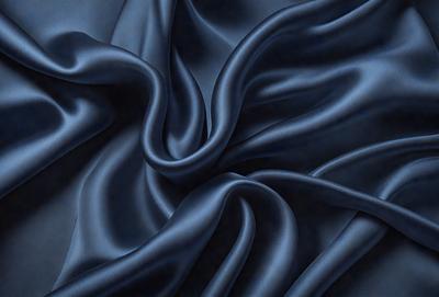 The primary subject of the image is a blue fabric, which appears to be a piece of cloth or a curtain. The setting is a dark room, and the visual style is a close-up of the fabric. The colors and mood of the image are predominantly dark and moody, with the blue fabric being the main focus.