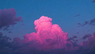 The primary subject of the image is a large, pink cloud in the sky. The cloud is the main focus of the image, and it appears to be a natural formation rather than a digital art or illustration. The sky serves as the setting, and the cloud appears to be the main object in the scene. The overall atmosphere of the image is vibrant and colorful, with the pink cloud standing out against the backdrop of the sky.
