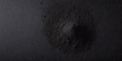 The primary subject of the image is a black substance, which appears to be a mixture of sand and dirt. The setting is a black background, which contrasts with the dark substance. The visual style is a close-up of the substance, showcasing its texture and composition. The colors and mood of the image are predominantly dark, with the black substance being the main focus.