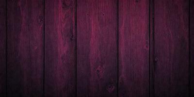 The primary subject of the image is a wooden wall with a purple tint. The setting is a room with a wooden floor. The visual style is a close-up of the wooden wall, which gives a sense of texture and depth. The colors and mood of the image are predominantly purple, creating a calm and serene atmosphere.