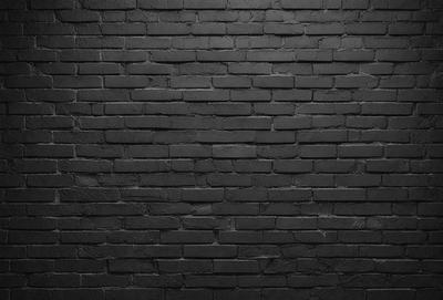 The primary subject of the image is a brick wall. The setting is a dark room, and the visual style is a black and white photo. The dominant colors are black and white, creating a moody atmosphere.