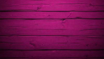 The primary subject of the image is a wooden wall with a purple hue. The setting is a room with a wooden floor, and the visual style is a close-up of the wooden wall. The dominant colors are purple and brown, creating a warm and inviting atmosphere.