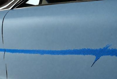 The primary subject of the image is a blue car with a blue line painted on it. The car is parked on a street, and the blue line is visible on the hood of the car. The setting is an outdoor environment, and the visual style appears to be a photo. The colors and mood of the image are predominantly blue, creating a calm and serene atmosphere.