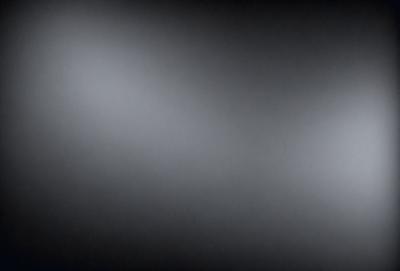 The image is a black and white photo of a dark room. The primary subject is a large, bright light source, which is located in the upper left corner of the image. The setting is a dark room, and the visual style is a black and white photo. The colors and mood of the image are predominantly dark and moody, with the bright light source being the only notable element of color.