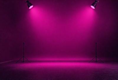 The primary subject of the image is a pink background with two lights shining on it. The setting is a studio, and the visual style is a photo. The dominant colors are pink, and the overall atmosphere is warm and inviting.