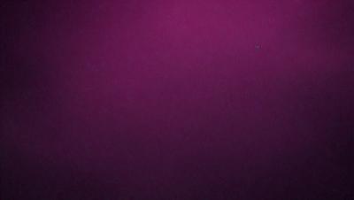 The primary subject of the image is a purple background. The setting is a dark, purple room with a pinkish hue. The visual style is a close-up of the purple background, which creates a moody and dramatic atmosphere.