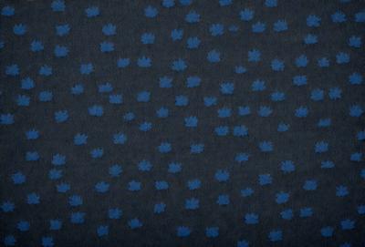 The primary subject of the image is a blue and white patterned fabric with a leaf design. The setting is a dark background, which contrasts with the light blue and white fabric. The visual style is a close-up of the fabric, showcasing the intricate details of the leaf pattern. The colors and mood of the image are predominantly blue and white, creating a calm and serene atmosphere.