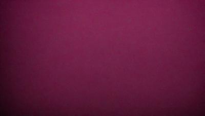 The primary subject of the image is a large, purple wall. The setting is a room with a dark background, which contrasts with the bright purple color of the wall. The visual style is a close-up of the wall, showcasing its vibrant hue. The colors and mood of the image are predominantly purple, creating a calm and serene atmosphere.