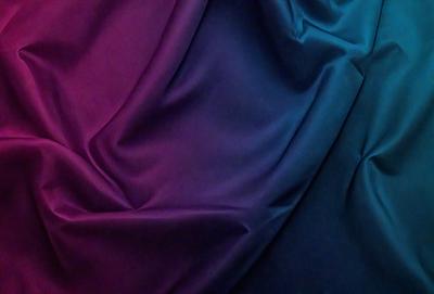 The primary subject of the image is a purple and blue fabric. The setting is a room with a colorful backdrop, and the visual style is a close-up of the fabric. The colors and mood of the image are vibrant and lively, with the purple and blue fabric creating a striking contrast against the colorful backdrop.