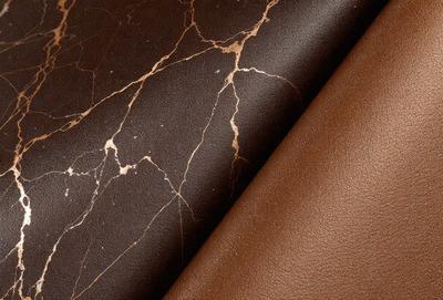 The primary subject of the image is a brown leather material, which is the main focus of the image. The setting is a table with a brown leather material on one side and a brown leather material on the other side. The visual style of the image is a close-up of the brown leather material, showcasing its texture and appearance. The colors and mood of the image are warm and earthy, with the brown leather material being the dominant color.