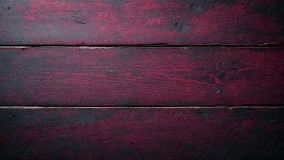 The primary subject of the image is a wooden surface with a red color. The setting is a wooden wall, and the visual style is a close-up of the wooden surface. The dominant colors are red and brown, creating a warm and natural atmosphere.