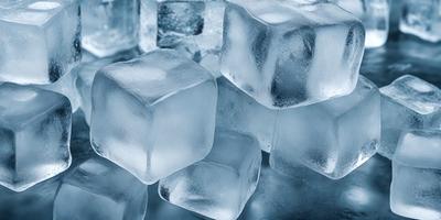 The primary subject of the image is a large pile of ice cubes. The ice cubes are arranged in a visually appealing manner, creating a sense of depth and dimension. The setting is a white surface, which provides a clean and uncluttered backdrop for the ice cubes. The visual style of the image is a close-up of the ice cubes, showcasing their intricate details and textures. The colors and mood of the image are predominantly blue and cold, as the ice cub