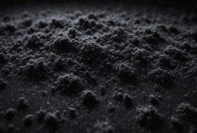 The primary subject of the image is a black and white photo of a dark, textured surface. The setting appears to be a dark room, and the visual style is a close-up of the textured surface. The colors and mood of the image are predominantly dark and moody, with the black and white color scheme adding to the atmosphere.