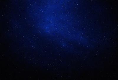 The primary subject of the image is the night sky, which is filled with stars. The setting is a dark, star-filled sky, and the visual style is a photo. The colors and mood of the image are predominantly dark and serene, with the stars providing a sense of wonder and tranquility.