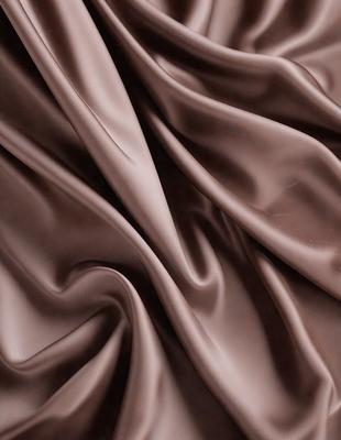 The primary subject of the image is a brown fabric, possibly a piece of velvet, with a wrinkled texture. The setting is a close-up view of the fabric, showcasing its intricate details. The visual style is a realistic representation of the fabric, capturing its natural texture and appearance. The colors and mood of the image are warm and earthy, with the brown fabric being the dominant color.