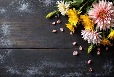 The primary subject of the image is a bouquet of flowers, which are placed on a wooden table. The setting is a black table, and the visual style appears to be a photo. The colors in the image are predominantly white and pink, creating a calm and serene atmosphere.